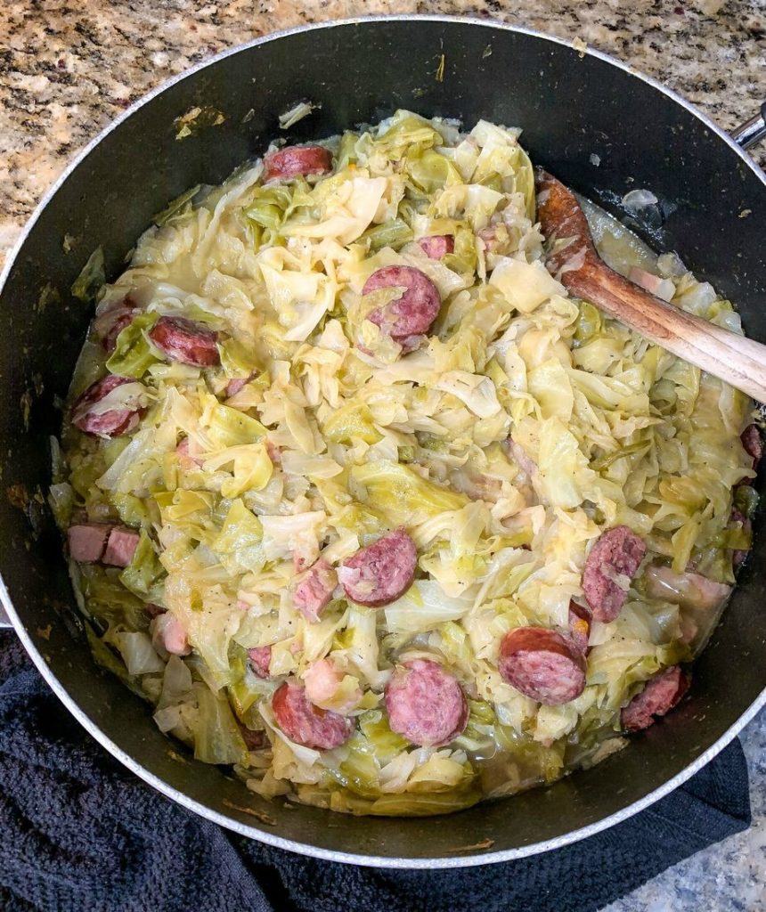 Southern Fried Cabbage With Sausage stirring and adding seasoning 