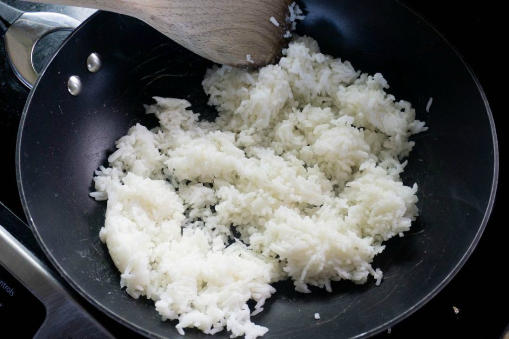 Wok with wooden spoon preparing the rice recipe