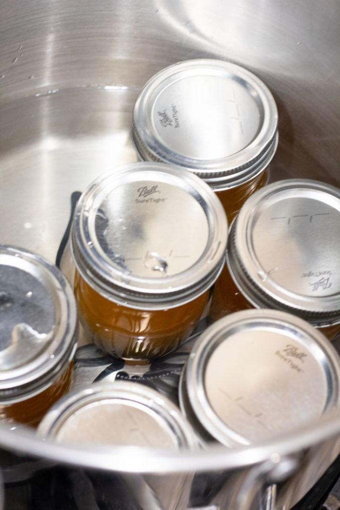 Jars of Satsuma Jelly in a water bath in a pot.