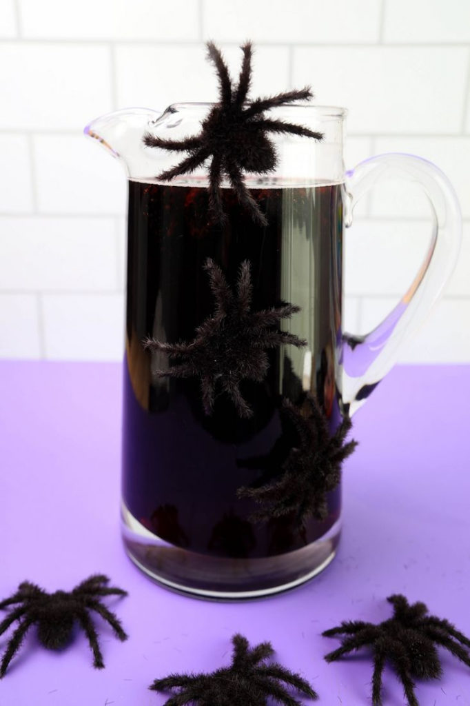 Purple Cocktail with blackberries in glass pitcher with spiders