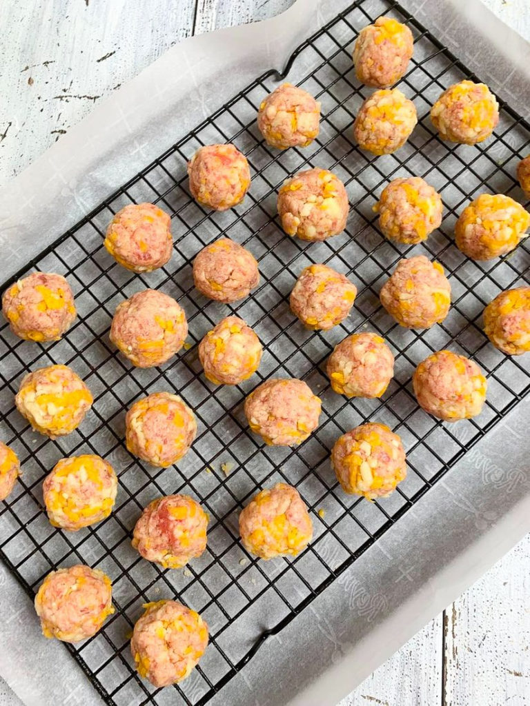 Round balls of sausage and cheddar cheese mixture on wire rack.
